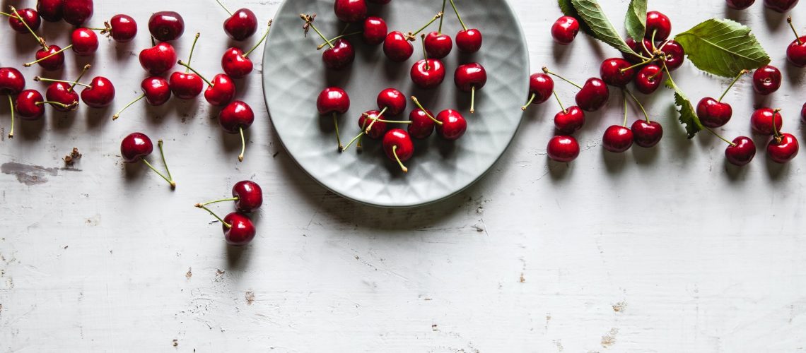 sweet cherries in a plate on an old white background, healthy food, fruits